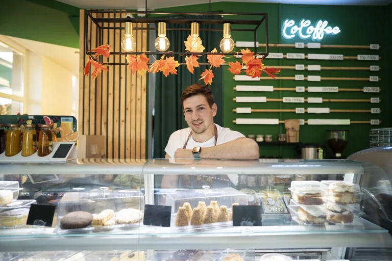 The person standing behind the counter of the coffee shop
