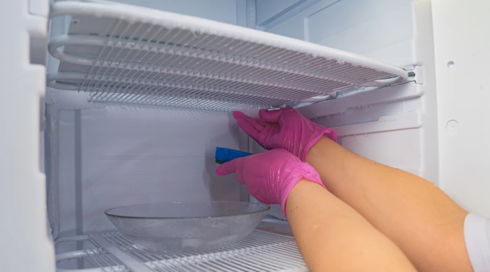 Frost-Free vs Manual Defrost: Which System Wins on Food Safety插图 a person is cleaning the frozen refrigerator